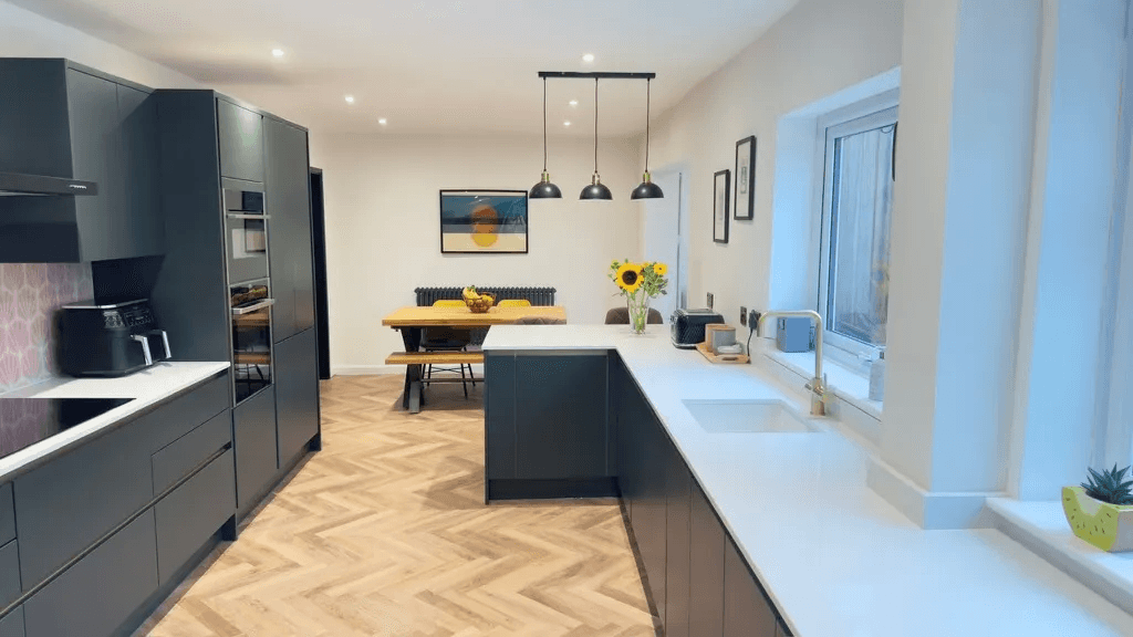 A fitted kitchen with dark cabinetry and herringbone flooring