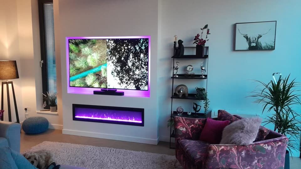 A bespoke media wall with a recessed television and electric fireplace